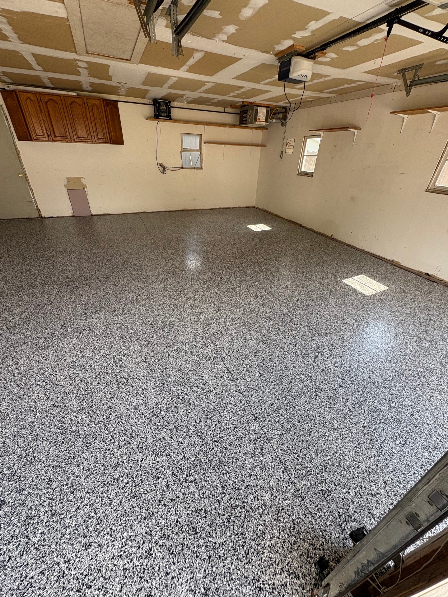Garagem vazia com pavimento em flocos cinzentos e armários castanhos